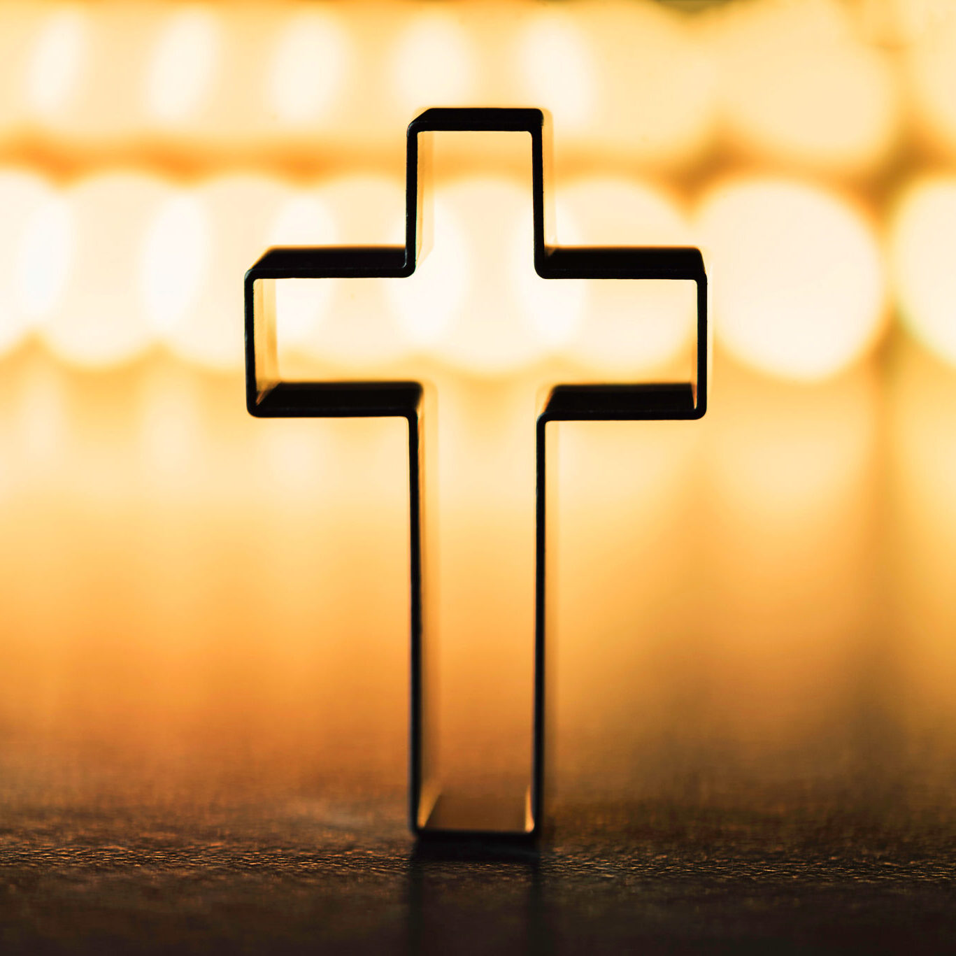 Silhouette of christian cross on yellow background, soft bokeh lights background. Copy space. Church worship, salvation concept. Faith symbol in Jesus Christ. Holy cross for Christmas, Easter day Silhouette of christian cross on yellow background, soft bokeh lights background. Copy space. Church worship, salvation concept. Faith symbol in Jesus Christ. Holy cross for Christmas, Easter day.